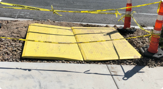 Pedestrian trench plates covering open utility trench.