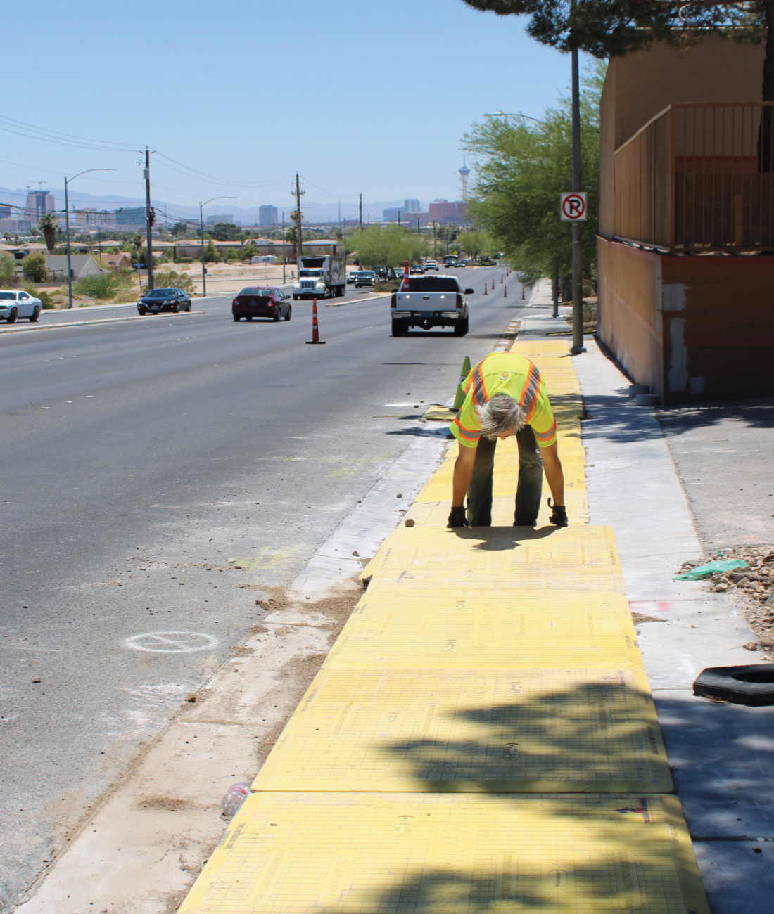 Worker placing pedestrian trench plate cover on sidewalk